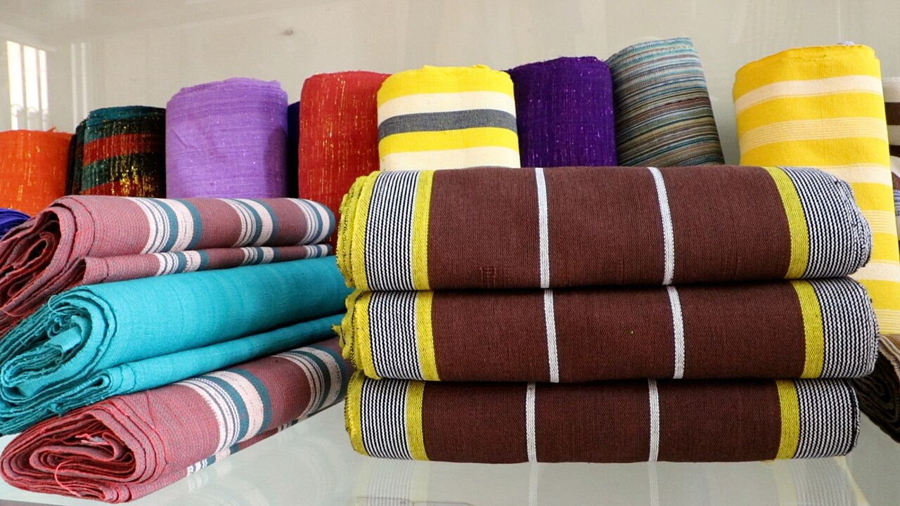 Rolls and stacks of colorful handwoven Faso Dan Fani cotton cloth